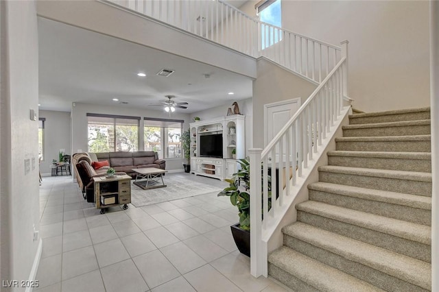 living room with light tile patterned floors, visible vents, recessed lighting, and a towering ceiling