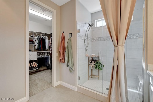 full bathroom with a walk in closet, baseboards, visible vents, and a shower stall