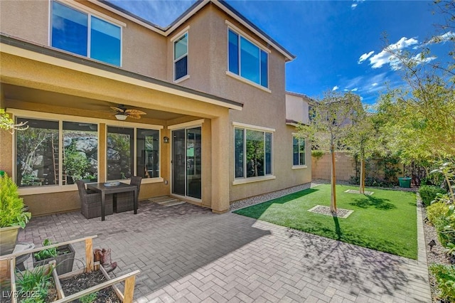 back of house featuring stucco siding, a lawn, a patio, and fence