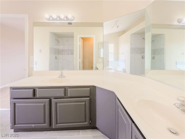 full bathroom with double vanity, visible vents, tiled shower, and a sink