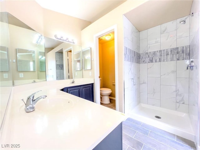 bathroom featuring a tile shower, toilet, and vanity