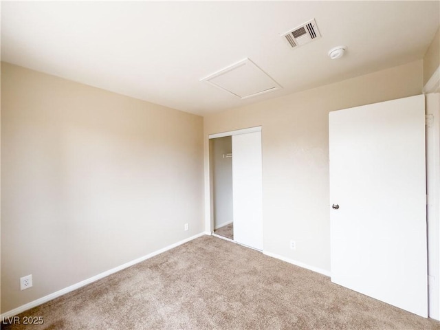 empty room featuring attic access, carpet flooring, baseboards, and visible vents