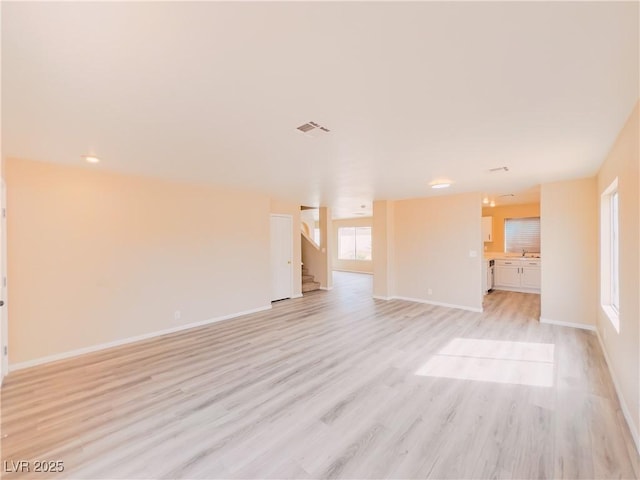 unfurnished living room with visible vents, baseboards, light wood-style flooring, and stairway