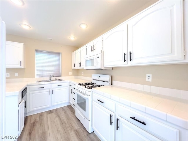 kitchen with white appliances, recessed lighting, a sink, white cabinets, and light wood-style floors