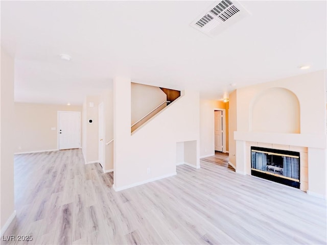 unfurnished living room with visible vents, a fireplace, baseboards, and wood finished floors