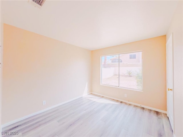 unfurnished room with visible vents, light wood-style flooring, and baseboards