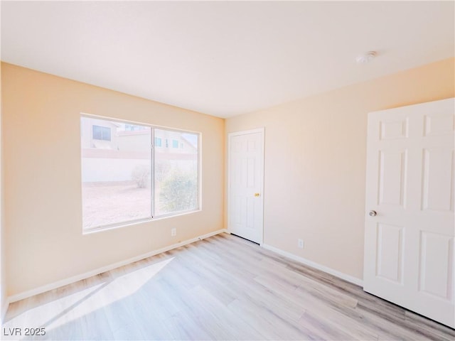 empty room featuring baseboards and light wood finished floors