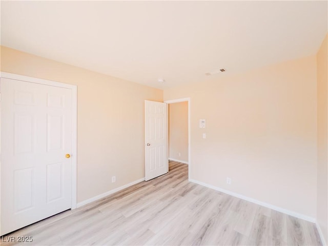 unfurnished room featuring baseboards and light wood-type flooring