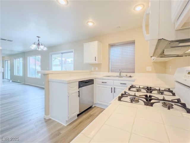 kitchen with visible vents, a peninsula, stainless steel dishwasher, white cabinetry, and a sink