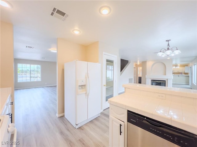 kitchen featuring visible vents, open floor plan, white fridge with ice dispenser, dishwasher, and tile counters