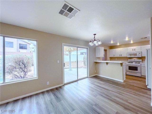 kitchen featuring white appliances, visible vents, a peninsula, light countertops, and white cabinetry