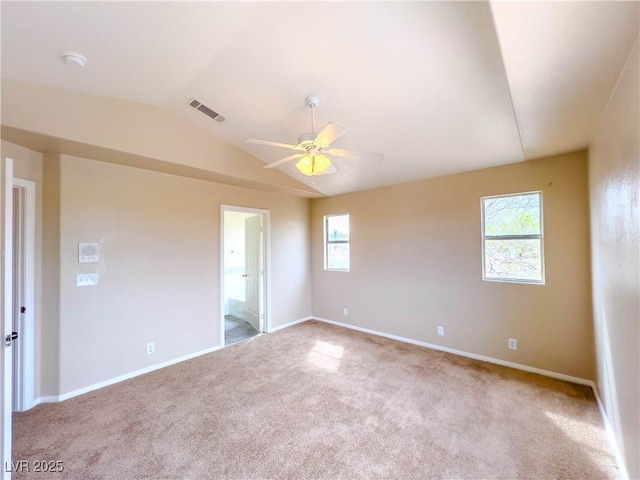 unfurnished room featuring vaulted ceiling, a healthy amount of sunlight, visible vents, and light carpet