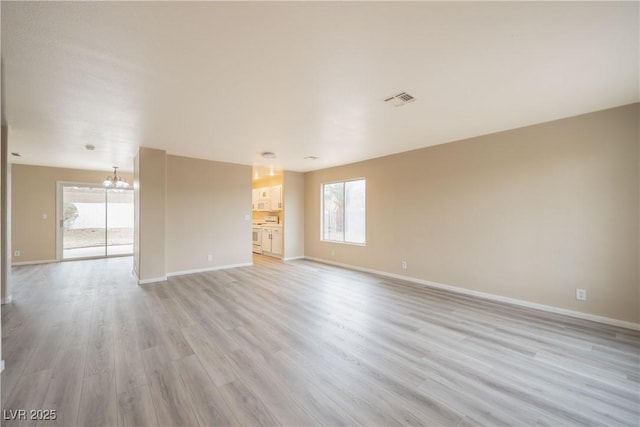 unfurnished living room with visible vents, baseboards, light wood-type flooring, and an inviting chandelier