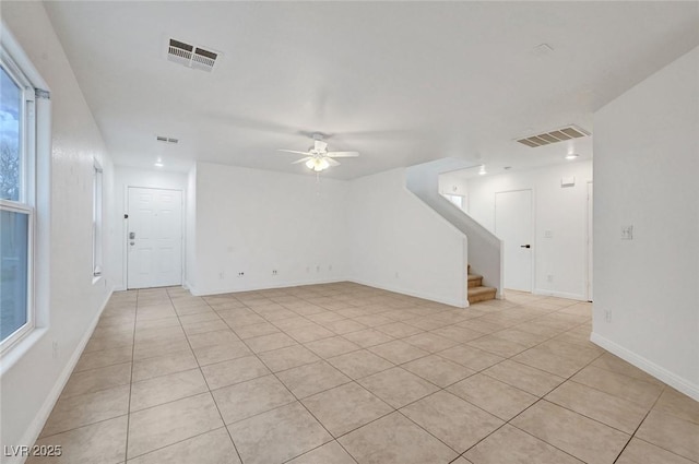 unfurnished room with visible vents, stairway, baseboards, and a ceiling fan