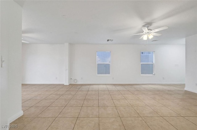 empty room with visible vents, a healthy amount of sunlight, baseboards, and a ceiling fan