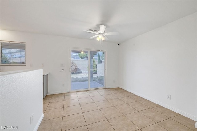 empty room featuring light tile patterned floors, a ceiling fan, and baseboards