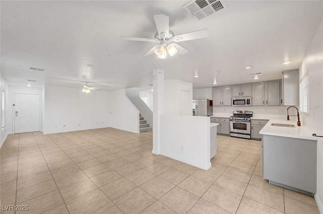 kitchen with visible vents, gray cabinets, a sink, ceiling fan, and stainless steel appliances