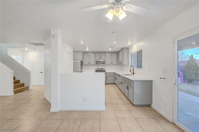 kitchen featuring gray cabinets, stainless steel appliances, ceiling fan, and a sink