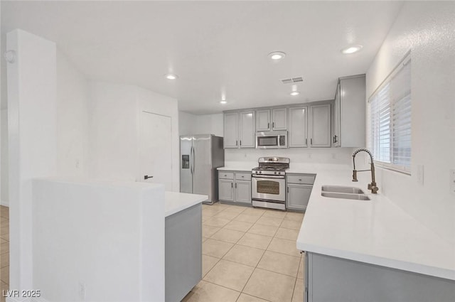 kitchen featuring a sink, stainless steel appliances, gray cabinetry, and light countertops