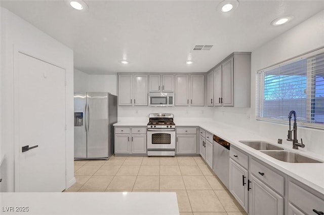 kitchen featuring visible vents, gray cabinets, light tile patterned flooring, stainless steel appliances, and a sink