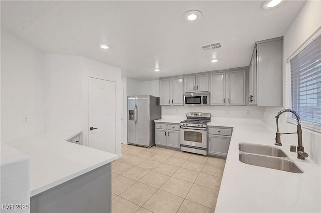 kitchen with visible vents, gray cabinetry, light countertops, appliances with stainless steel finishes, and a sink