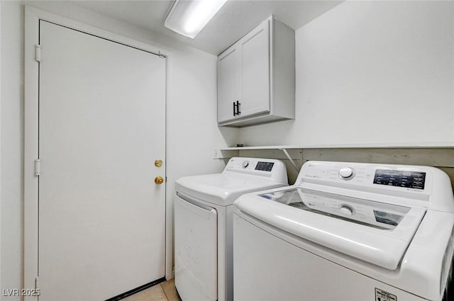 clothes washing area with light tile patterned flooring, cabinet space, and independent washer and dryer