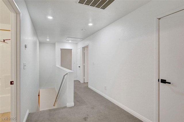 hallway featuring carpet, visible vents, baseboards, recessed lighting, and an upstairs landing