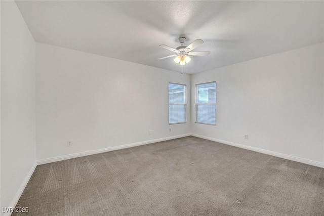 carpeted empty room featuring baseboards and ceiling fan