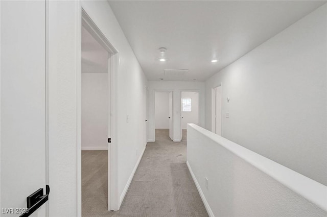 hallway with light carpet, an upstairs landing, and baseboards