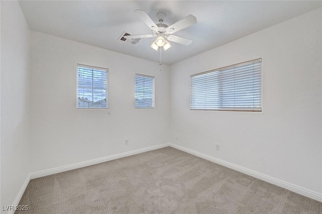 carpeted spare room featuring baseboards and ceiling fan