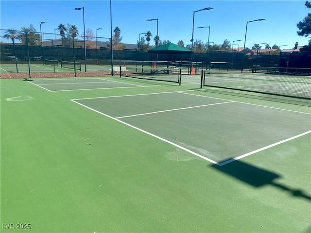 view of tennis court featuring community basketball court and fence