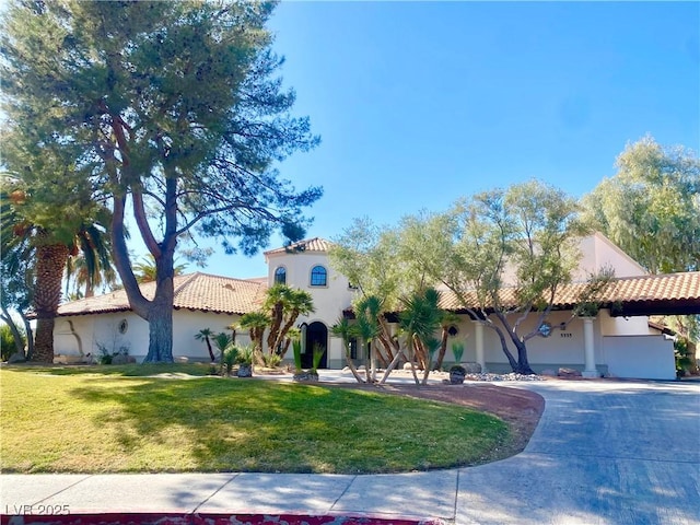 mediterranean / spanish home featuring stucco siding, concrete driveway, a tile roof, and a front lawn