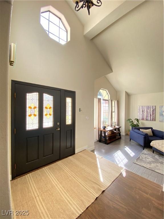 foyer featuring baseboards, high vaulted ceiling, and wood finished floors