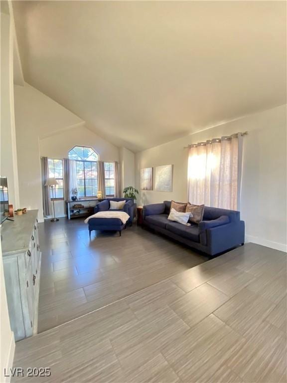 living room featuring baseboards and lofted ceiling