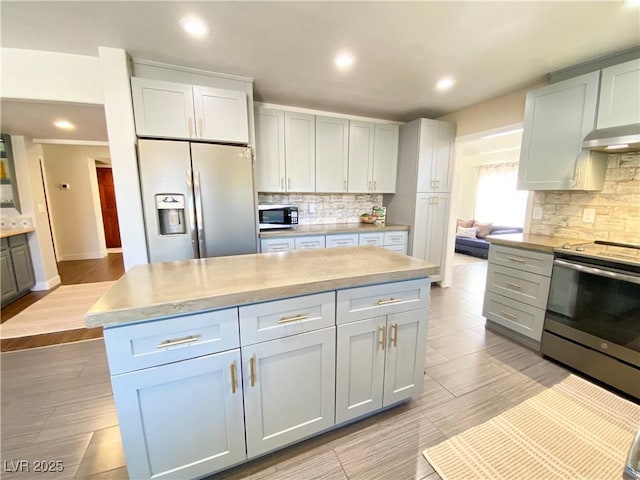 kitchen with stainless steel electric range oven, a kitchen island, light countertops, under cabinet range hood, and fridge with ice dispenser