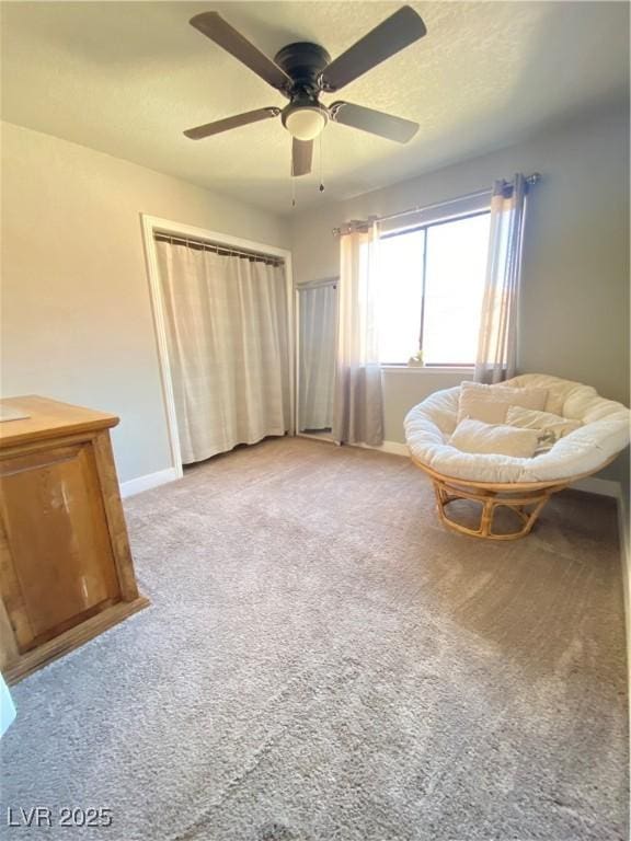 sitting room with a ceiling fan, baseboards, carpet floors, and a textured ceiling