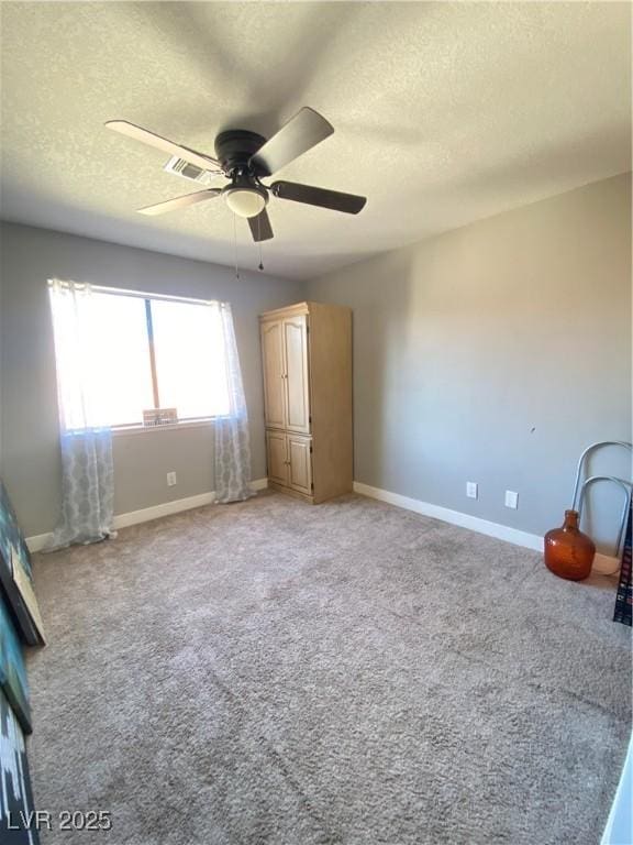 unfurnished bedroom with visible vents, baseboards, ceiling fan, a textured ceiling, and light carpet