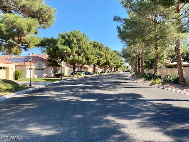 view of street featuring street lights, curbs, and a residential view