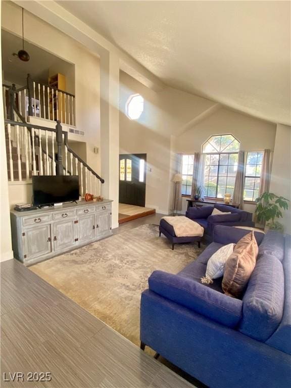 carpeted living area with high vaulted ceiling and stairs