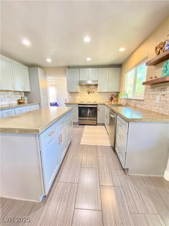 kitchen featuring dishwasher, light countertops, decorative backsplash, stove, and a sink