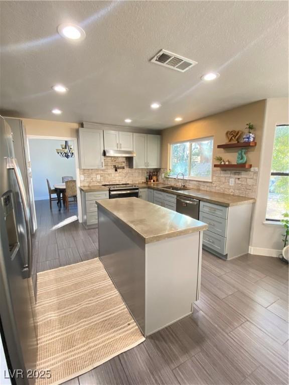 kitchen featuring stainless steel appliances, plenty of natural light, visible vents, and decorative backsplash