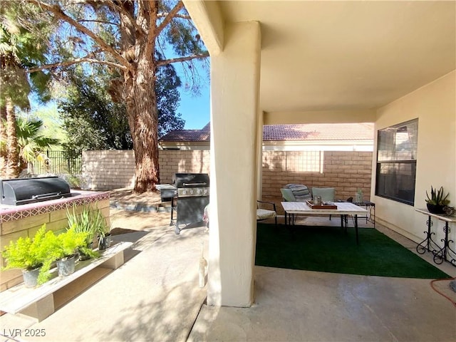 view of patio with area for grilling, exterior kitchen, and fence