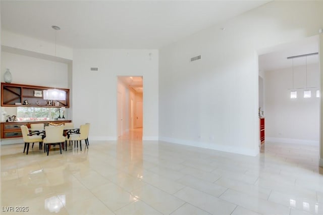 living area with light tile patterned floors, visible vents, and baseboards