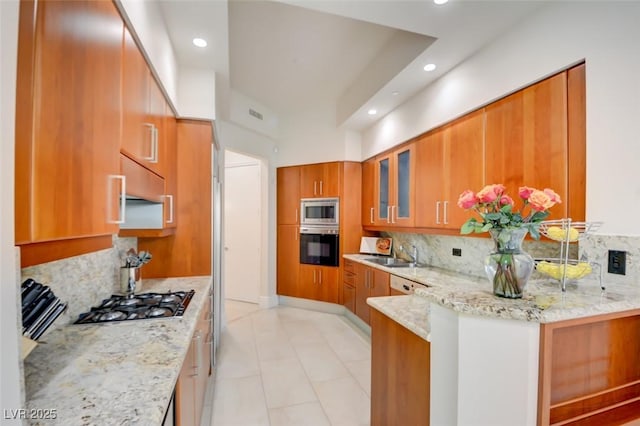 kitchen featuring a sink, light stone counters, brown cabinets, and appliances with stainless steel finishes