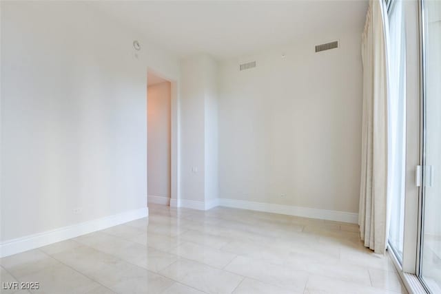 spare room with baseboards and visible vents