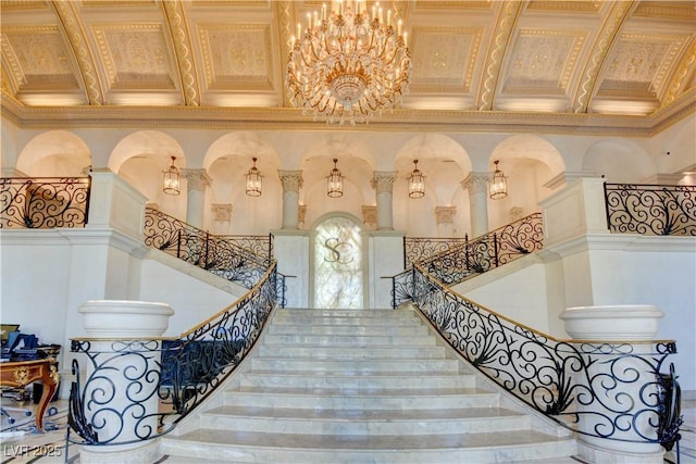 stairs featuring ornamental molding, a notable chandelier, and a towering ceiling