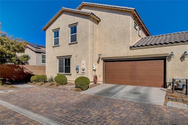 view of front of house featuring stucco siding, a tile roof, and a garage