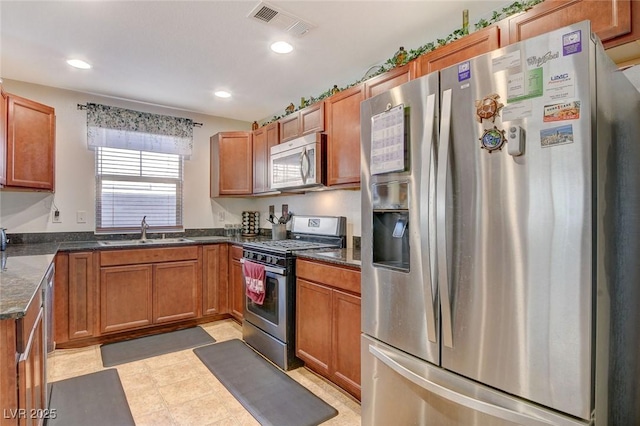 kitchen with a sink, stainless steel appliances, brown cabinets, and visible vents