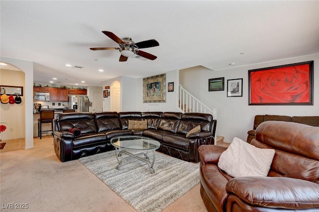 living area with visible vents, recessed lighting, arched walkways, light colored carpet, and stairs