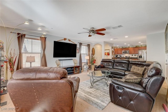 living area featuring visible vents, recessed lighting, arched walkways, light colored carpet, and ceiling fan